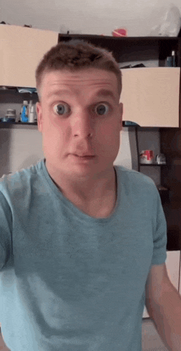 a man in a blue shirt making a surprised face