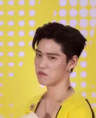 a young man wearing a yellow shirt is making a funny face .