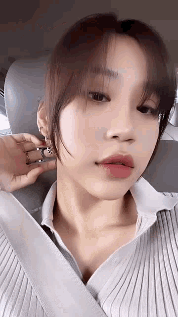 a close up of a woman wearing a seat belt and earrings .