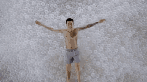 a man is laying on top of a pile of plastic balls .