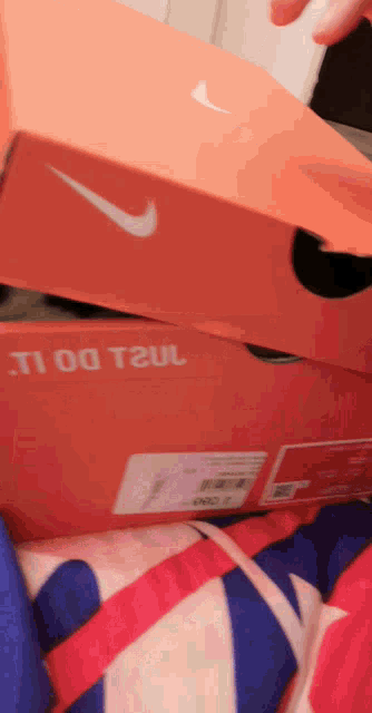 a pair of orange nike boxes stacked on top of each other on a bed
