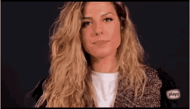 a woman with long blonde hair is wearing a sweater and a white t-shirt .