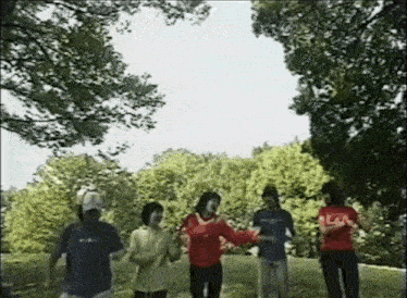 a group of people are dancing in a park and one of them is wearing a shirt that says coca cola on it