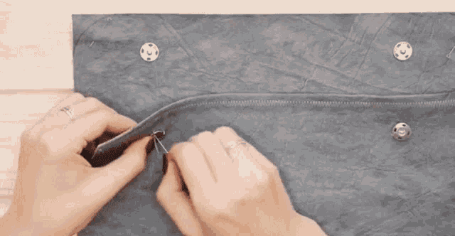 a person is holding a piece of leather with a zipper and buttons .