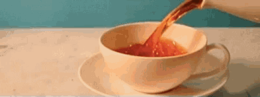 a cup of tea is being poured into a cup on a saucer .