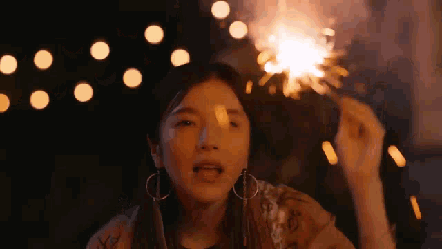 a woman is holding a sparkler in her hand at night
