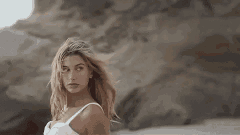 a woman in a white dress is standing on a beach .