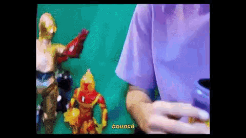 a person in a purple shirt is holding a can of soda in front of a bunch of action figures .
