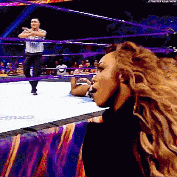 a woman is standing in a wrestling ring with a referee .