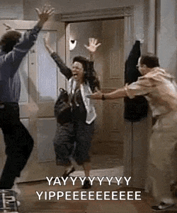 a man and a woman are jumping in the air in a doorway with their hands in the air .