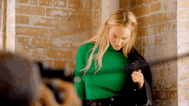 a woman in a green sweater is being photographed by a camera