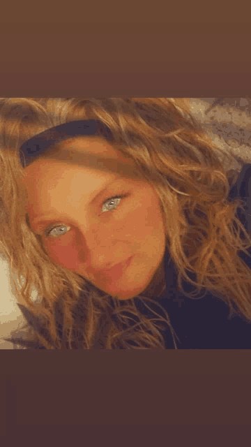 a woman with blonde hair and blue eyes is wearing a headband
