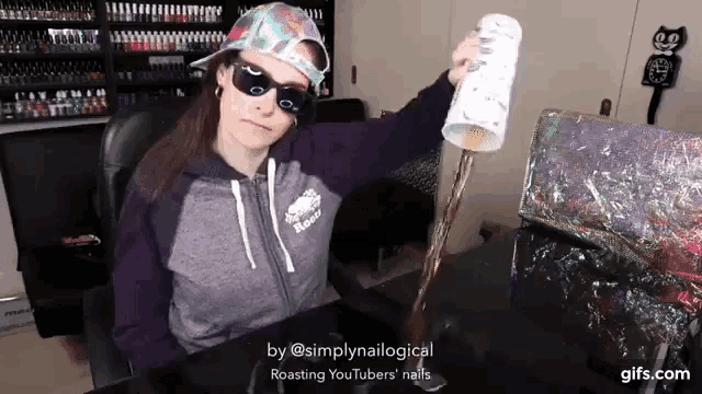 a woman wearing sunglasses and a hat is sitting at a desk holding a cup that says " roasting youtubers "
