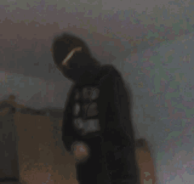 a blurry picture of a person in a hat standing in a dark room .