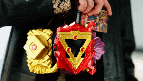 a person is holding a red and gold toy with a triangle in the middle .