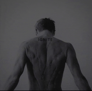 the back of a shirtless man with the word ignite on his back