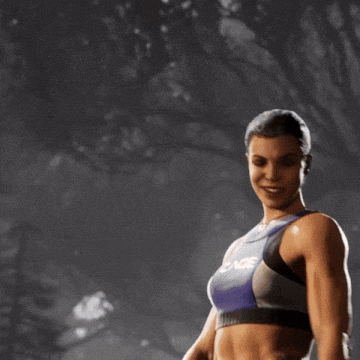 a woman in a cage top and shorts stands in a dark forest