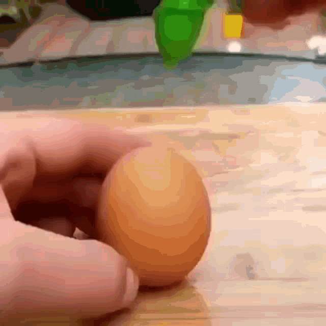 a close up of a person holding an egg on a cutting board