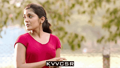 a woman in a red shirt stands in front of a sign that says kvvcsr