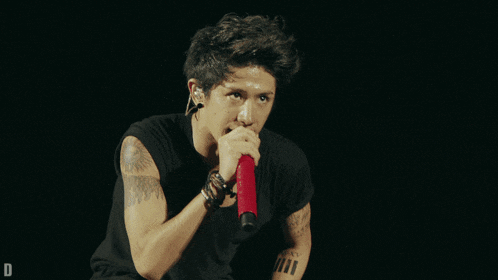 a man with a tattoo on his arm holds a microphone in his hand