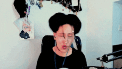a man wearing headphones is sitting in front of a microphone and making a funny face