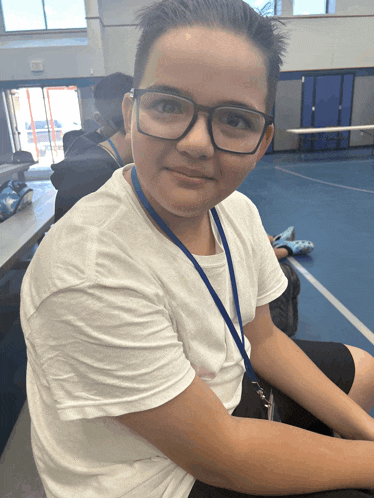 a boy with glasses and a lanyard around his neck