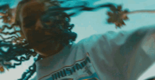 a woman with dreadlocks is wearing a mustang t-shirt .