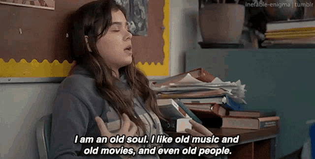 a girl is sitting at a desk and talking about old music and movies