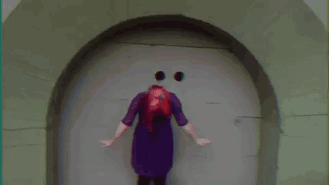 a woman in a purple dress is standing in front of a door with holes in it