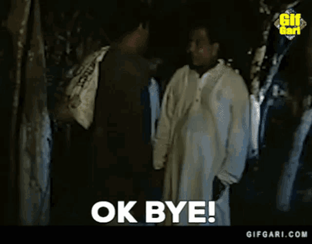 two men are standing next to each other in a forest and one of them is saying `` ok bye '' .
