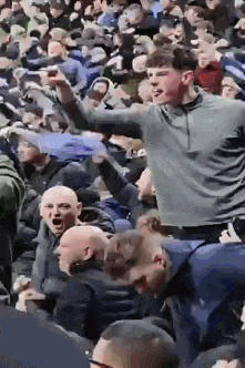 a man is standing in the middle of a crowd of people at a stadium .