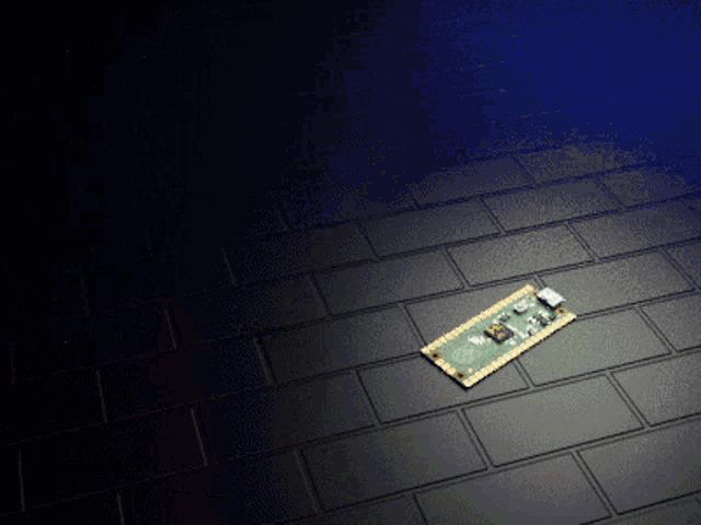 a green and gold motherboard is laying on a black tile floor