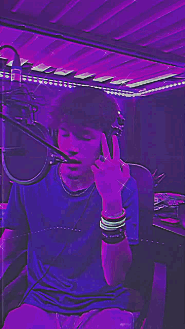 a man wearing headphones is giving the middle finger in front of a microphone