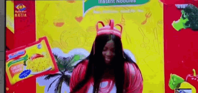 a woman is dancing in front of a box of instant noodles .
