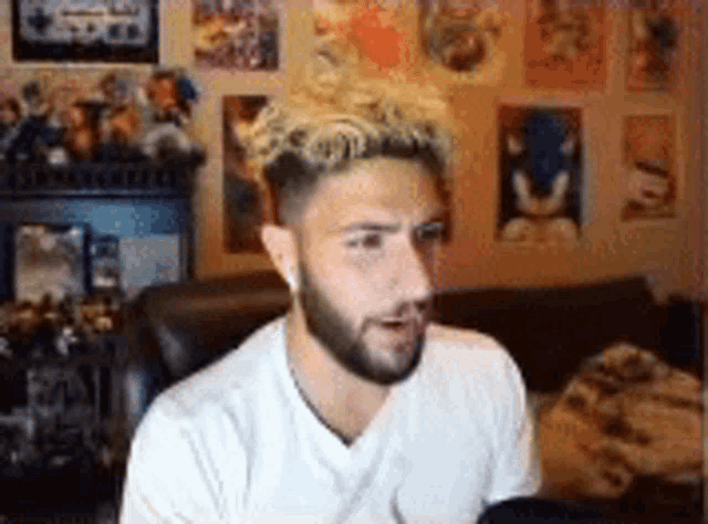 a man with a beard is sitting on a couch in front of a computer screen .