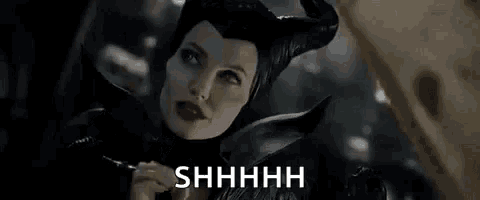 a woman in a black costume is holding her finger to her mouth .