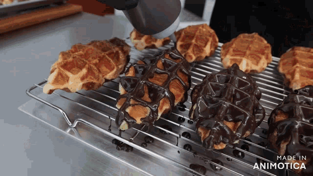 a bunch of waffles covered in chocolate are on a cooling rack made in animatica