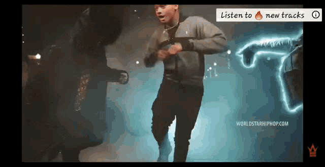 a man is dancing in front of a sign that says listen to new tracks .