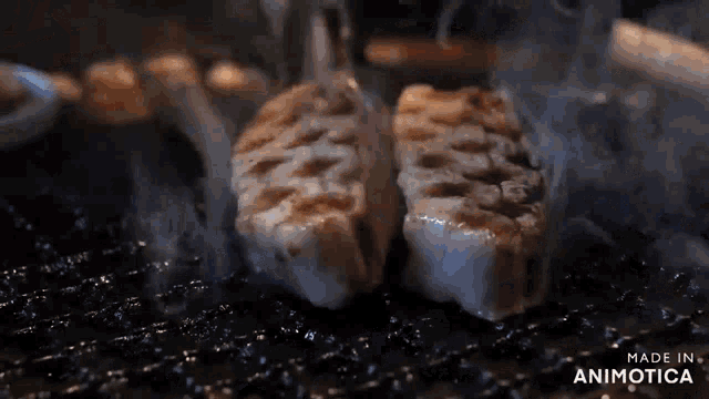 two pieces of meat are cooking on a grill with smoke coming out of it .