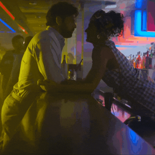 a man and a woman are kissing on a bar with a sign that says l on it