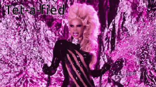 a drag queen is standing in front of a purple background holding a cane .