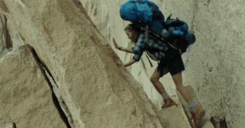 a person with a blue backpack is climbing a rock wall