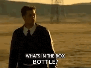 a man in a suit and tie is standing in a field and asking what 's in the box bottle ?
