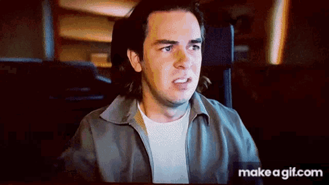 a man is sitting in front of a computer screen and making a face .