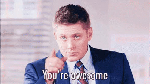 a man in a suit and tie is pointing his finger at the camera and saying `` you 're awesome '' .