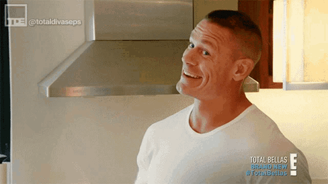 a man in a white shirt is smiling in front of a stainless steel hood that says total bellas