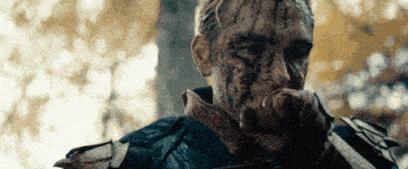 a man with blood on his face holds his fist up