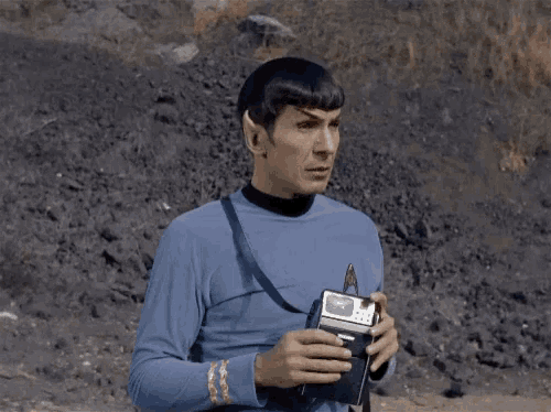 a man in a blue shirt is holding a remote control in his hands
