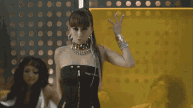 a woman in a black dress is standing in front of a yellow wall with polka dots