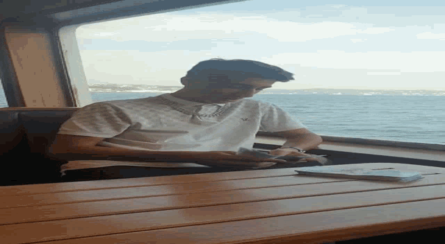 a man wearing a shirt that says ' abercrombie & fitch ' on it sits at a wooden table